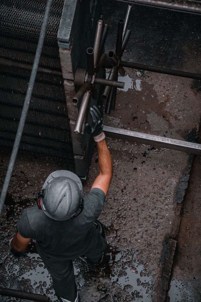 Aerial view of a worker in safety gear adjusting industrial machinery in a rugged outdoor setting.