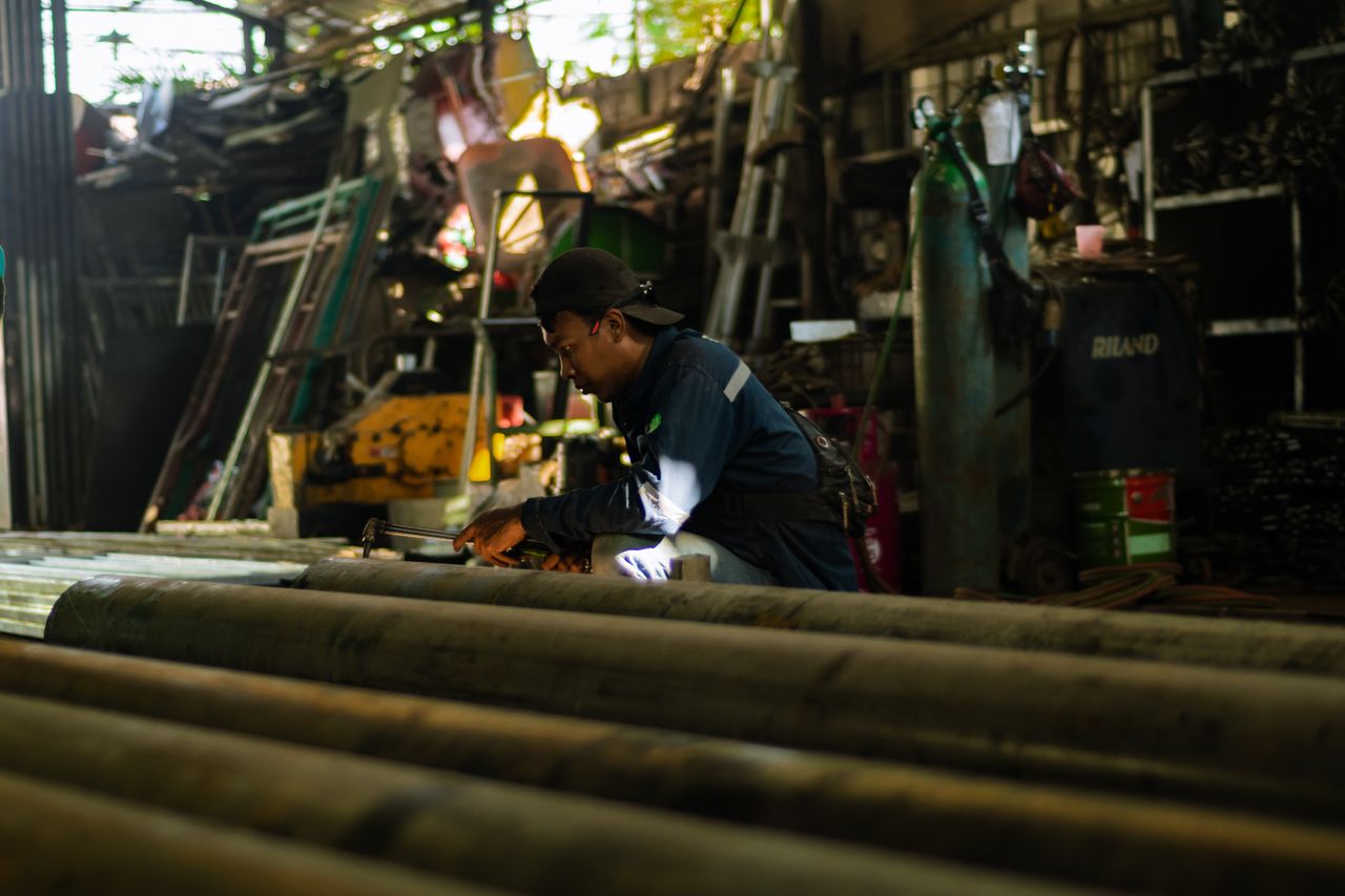 A focused artisan works diligently in a busy industrial workshop, showcasing modern craftsmanship.